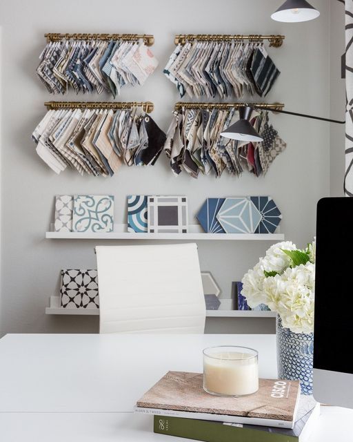 a white desk topped with a computer monitor next to a vase filled with flowers and books