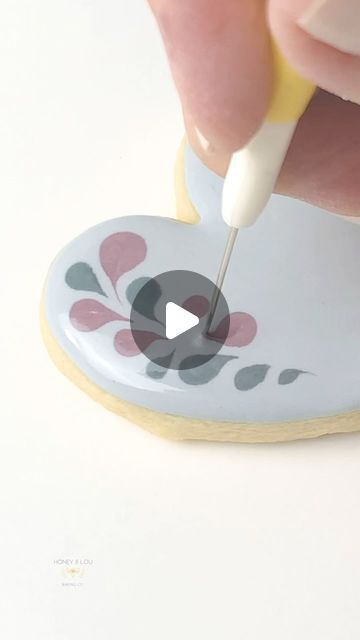 a person is using a marker to paint a heart shaped cookie with flowers on it