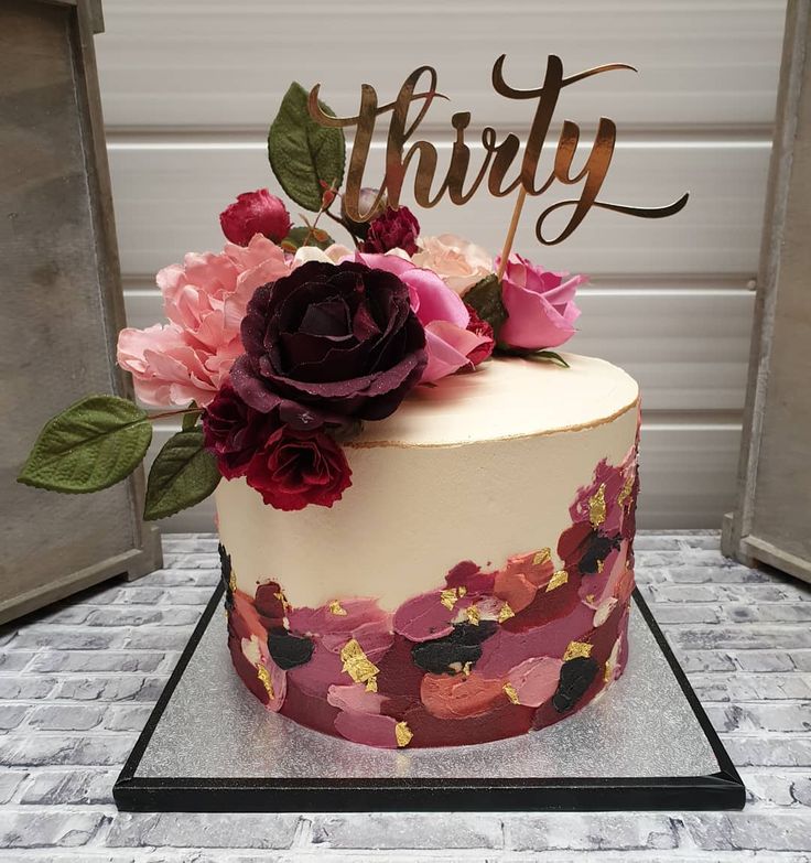 a cake decorated with flowers and the word thrift on top is sitting on a table