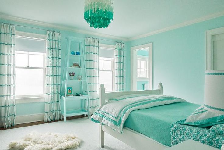 a bedroom with blue walls, white carpet and a green chandelier hanging from the ceiling