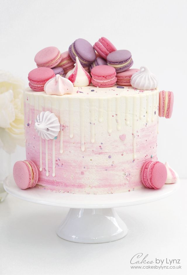 a pink and white cake with macaroons on top