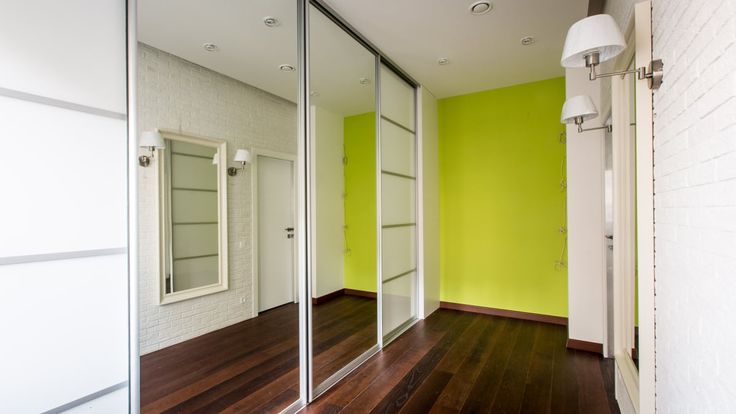 an empty room with green walls and wooden flooring is seen through the glass doors