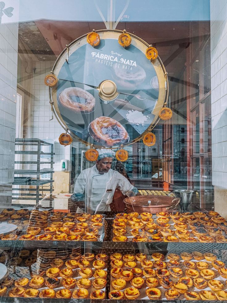 a man standing in front of a display case filled with pastries