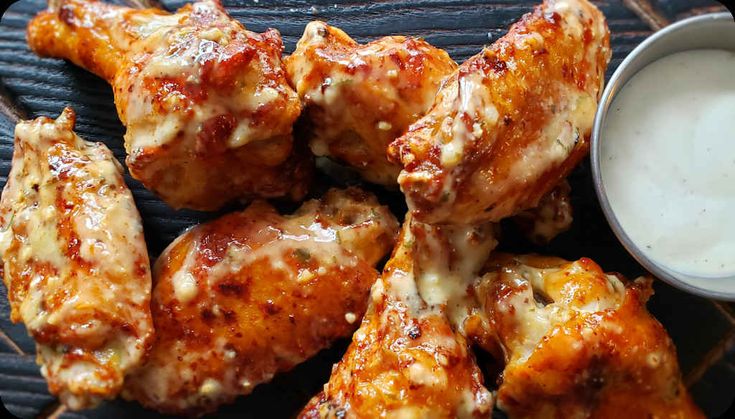 chicken wings with dipping sauce on a black plate