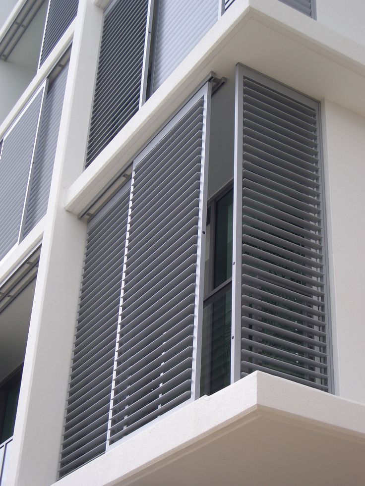 a tall white building with lots of windows and shutters on the side of it