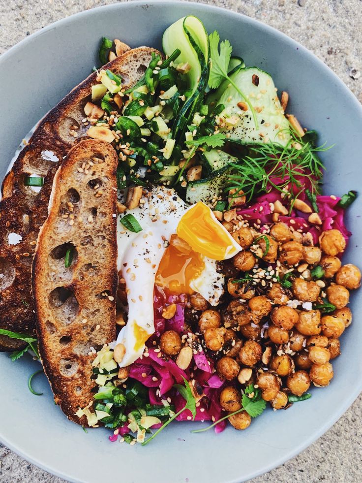 a blue bowl filled with bread, vegetables and chickpeas on top of it