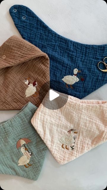 three baby bibs with embroidered animals on them, one is blue and the other is brown