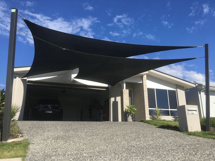 a black awning over a driveway next to a house