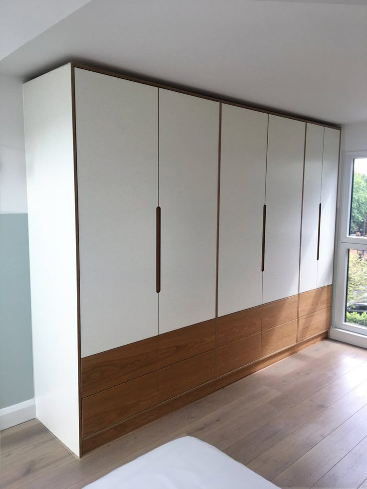 an empty bedroom with white and wood furniture