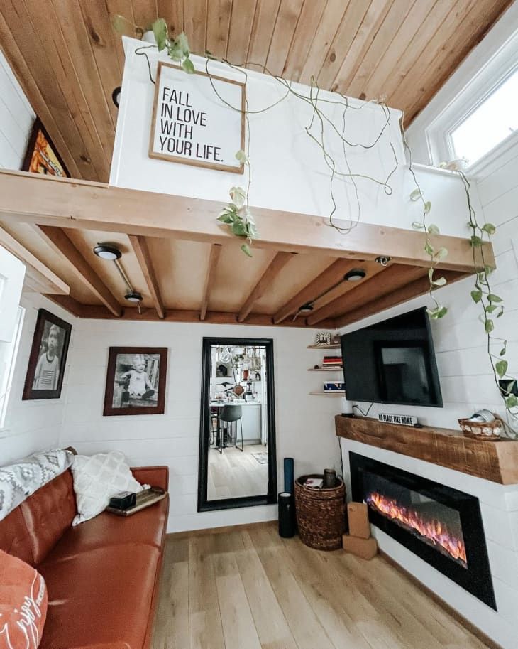 a living room with a couch, fireplace and tv on the top shelf above it