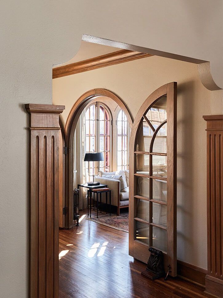 an arched doorway leads into a living room with hardwood floors and walls, along with a wood floor