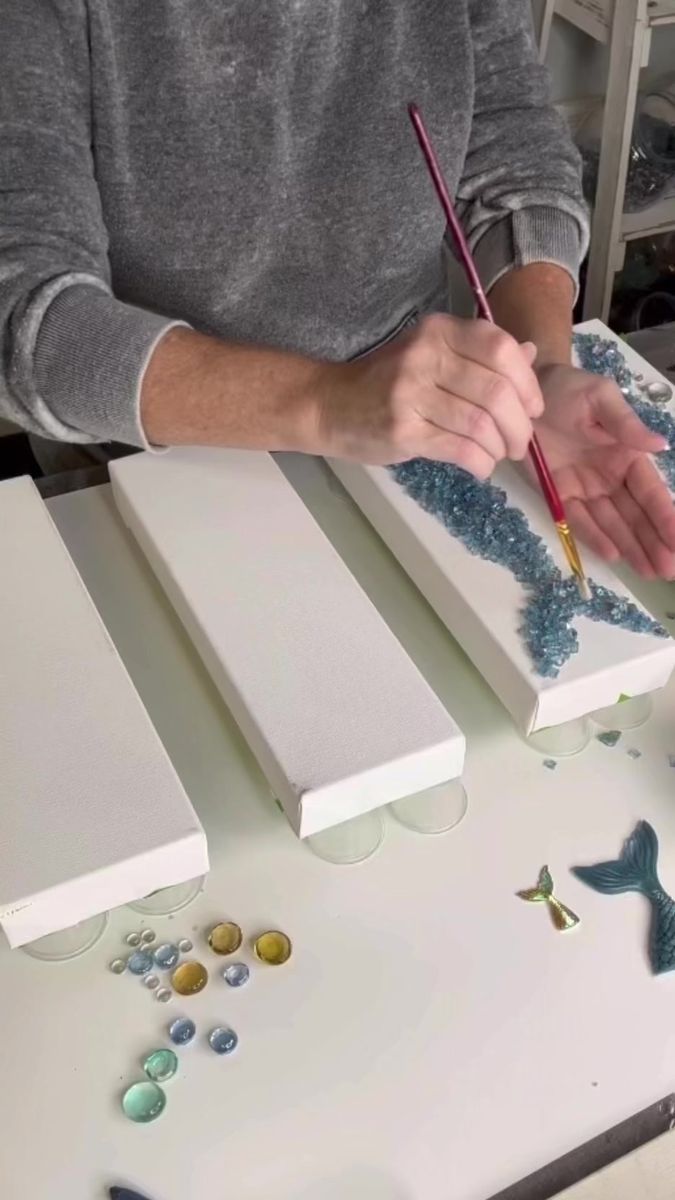 a man is painting some white and blue designs on the table with a pencil in his hand