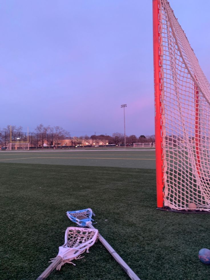 a soccer goal and ball on the grass in front of an empty field at dusk