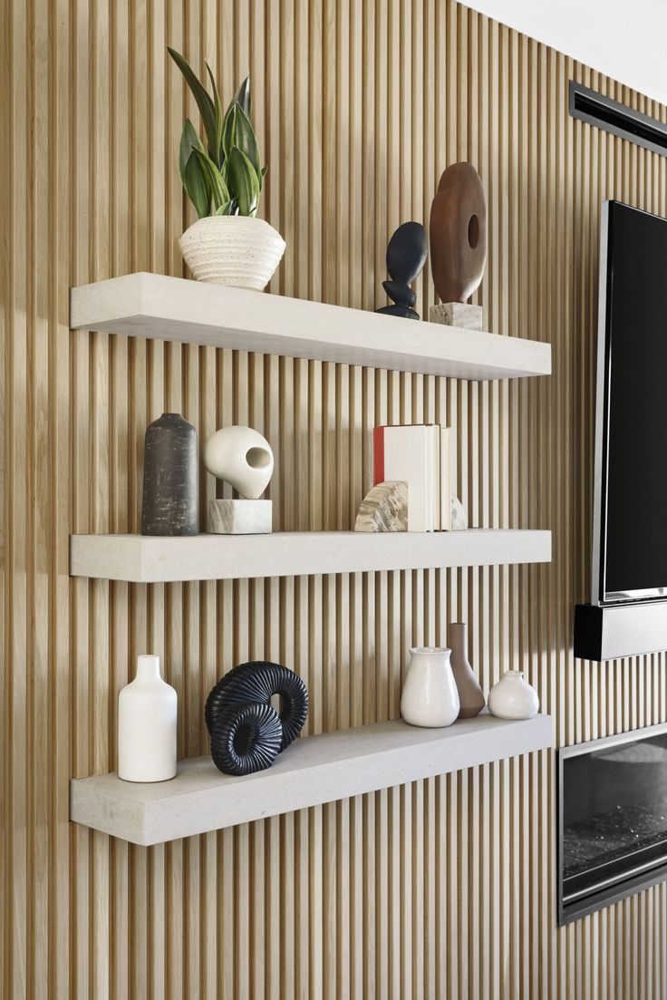 three white shelves with vases and other items on them in front of a flat screen tv