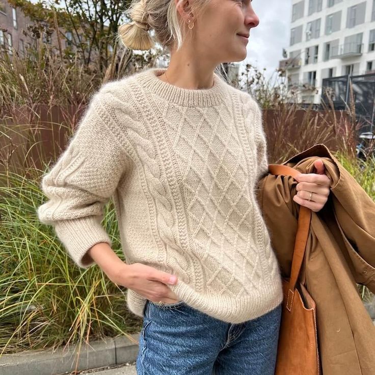 a woman is standing on the sidewalk with her hand in her pocket and looking off into the distance