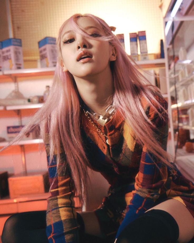 a woman with long pink hair sitting on the floor in front of shelves and boxes