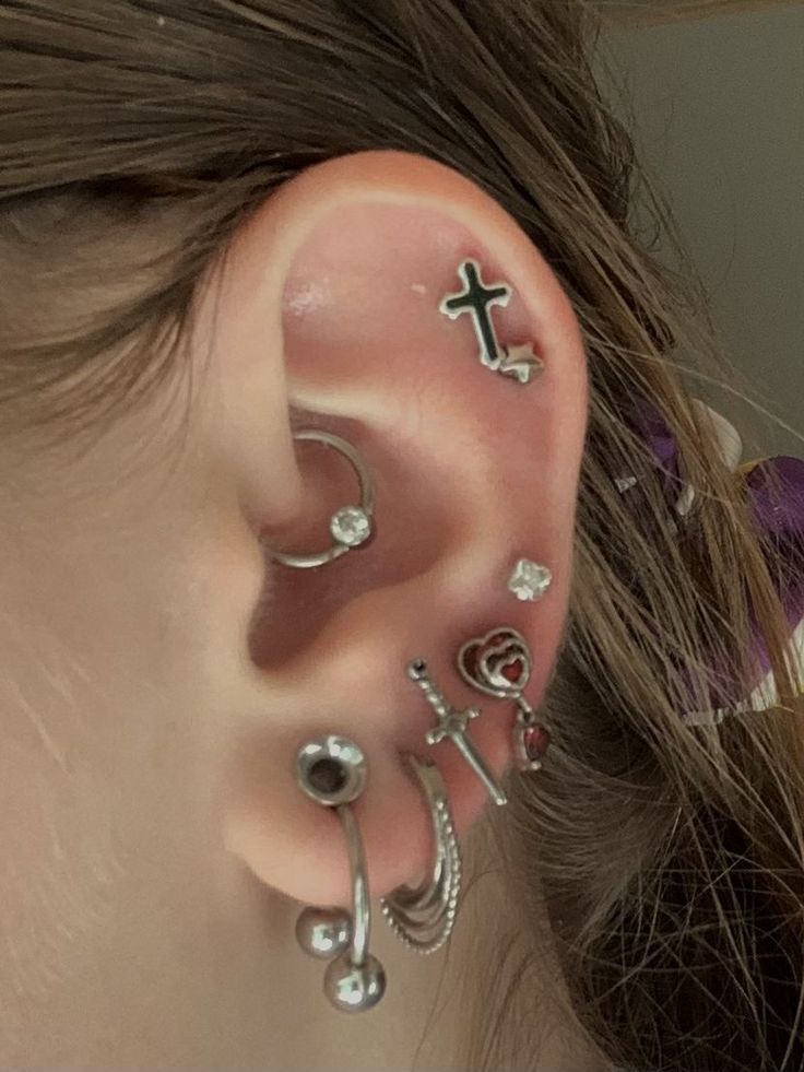 a close up of a person's ear with different piercings on the side