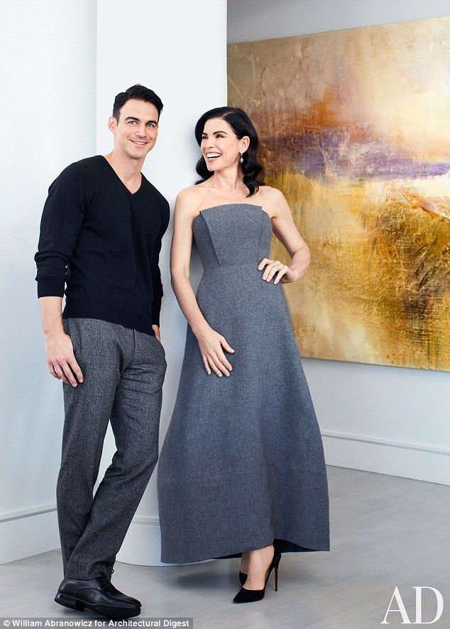 a man and woman standing next to each other in front of a painting on the wall