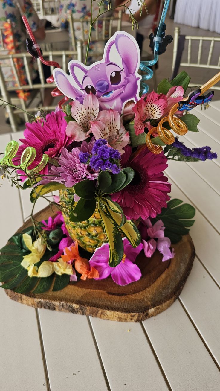 a vase filled with flowers sitting on top of a wooden table next to a sign