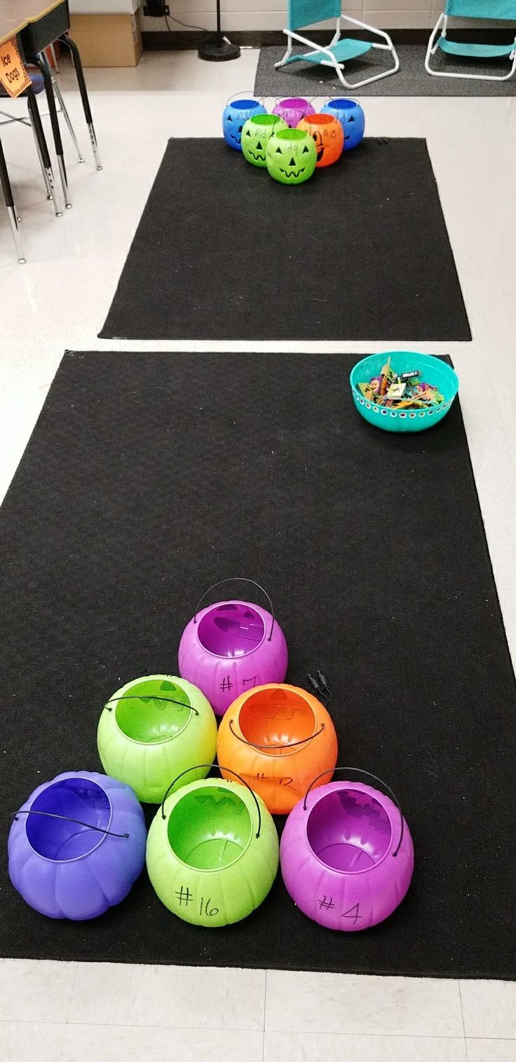 there are many different colored bowls on the black mat in the room with chairs and tables