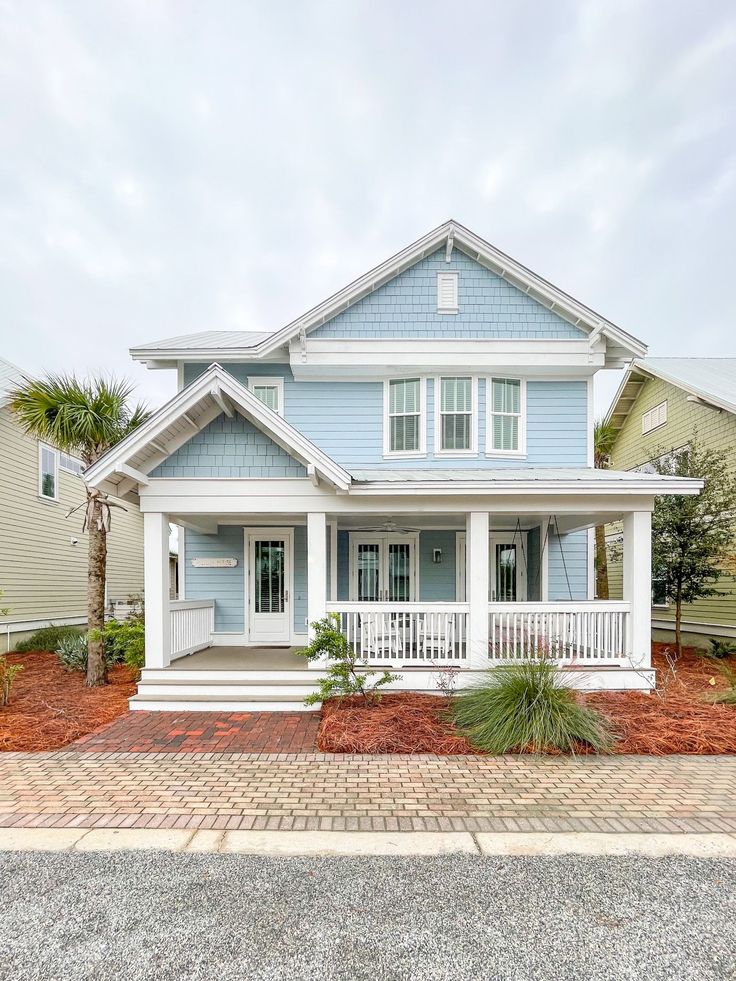 a blue and white house with palm trees in the front yard