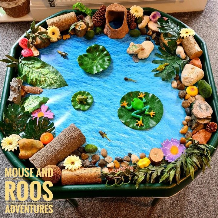 a frog pond made out of rocks and leaves on top of a table with water