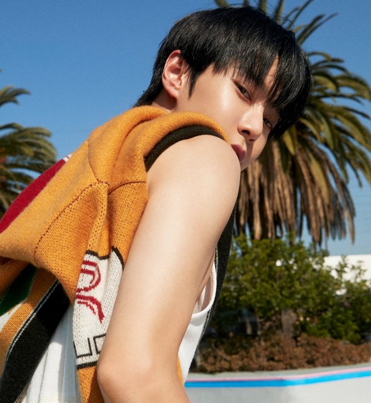 a young man carrying a skateboard on his back with palm trees in the background