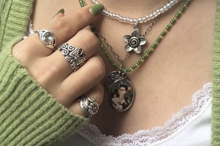 a woman wearing rings and necklaces with pictures on them