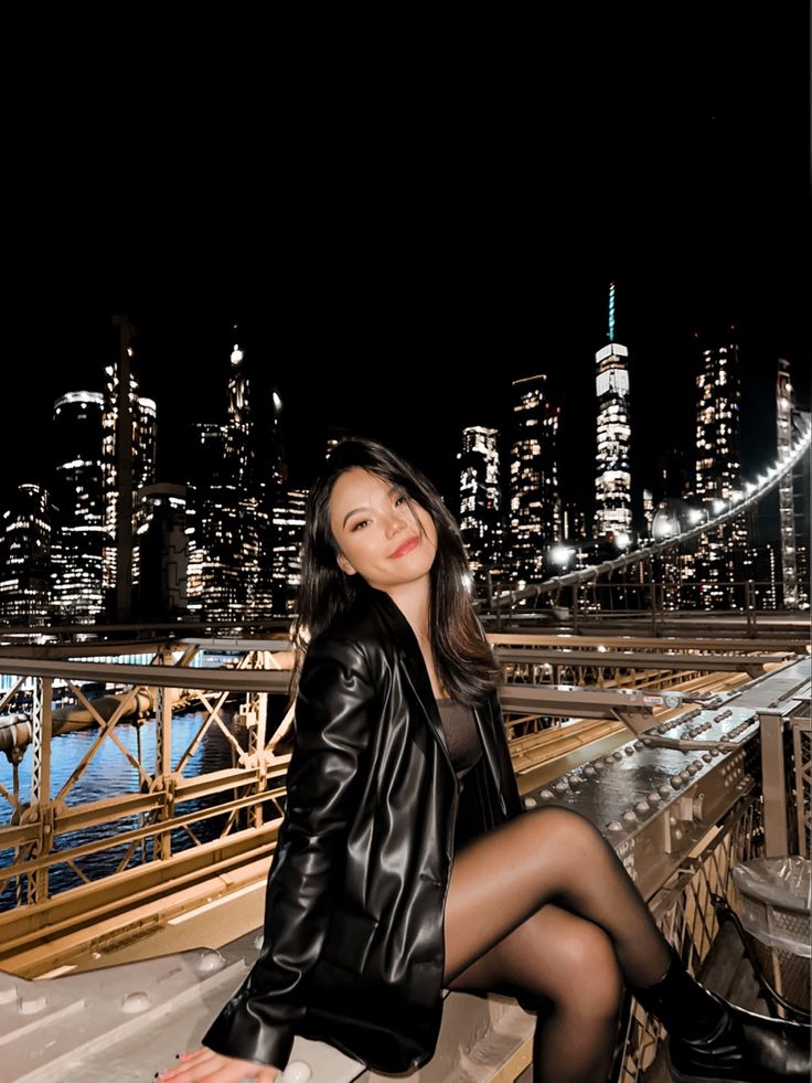 a woman sitting on top of a wooden bench in front of a cityscape