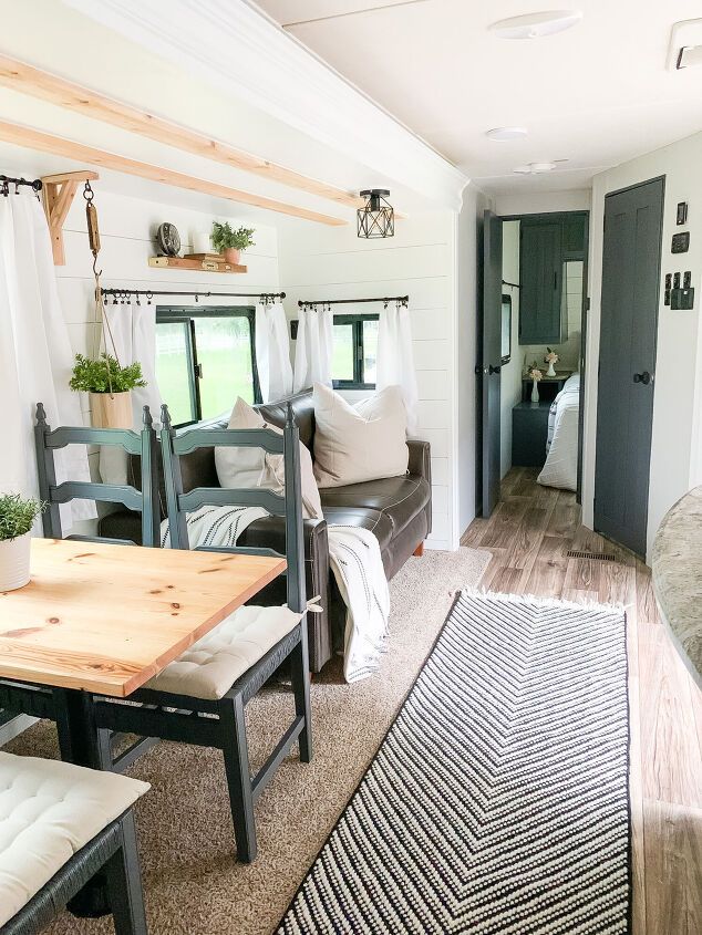 a living room and dining area in a tiny home with wood floors, white walls and windows