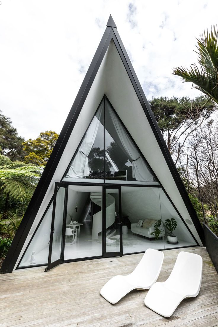 two white lounge chairs sitting on top of a wooden deck next to a building with glass windows