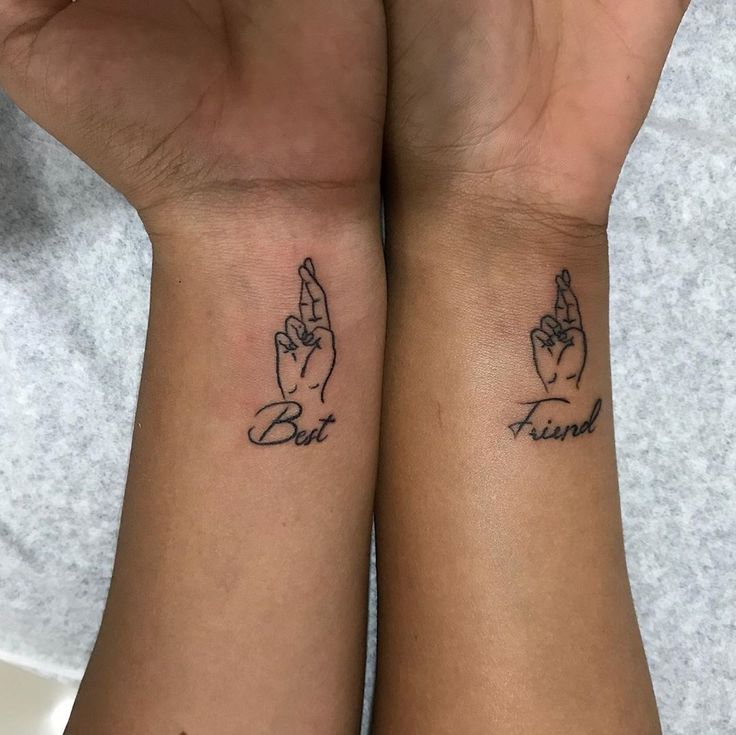 two wrist tattoos with the words best friend and sister written on their wrists, both holding hands together