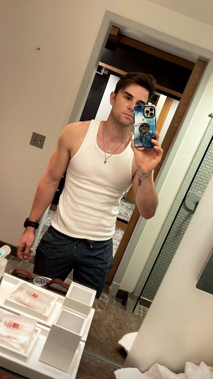 a man taking a selfie in front of a bathroom mirror with his cell phone