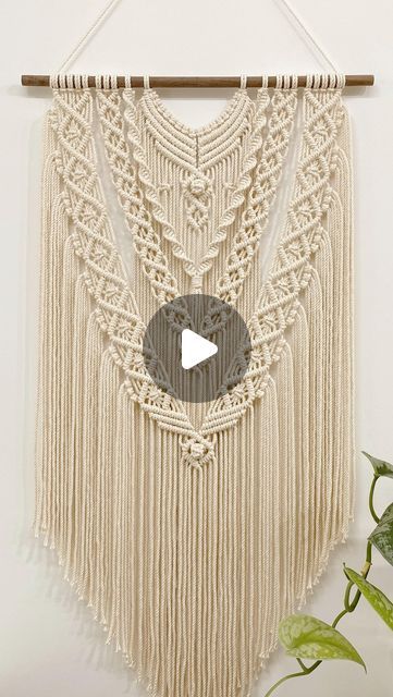 a macrame wall hanging with a video play button on the bottom right corner