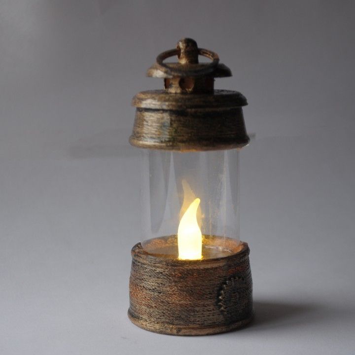 an old fashioned oil lamp with a candle burning in it's glass holder on a gray background