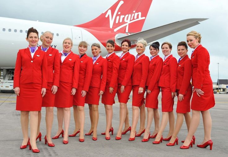 a group of women in red uniforms standing next to an airplane on the tarmac