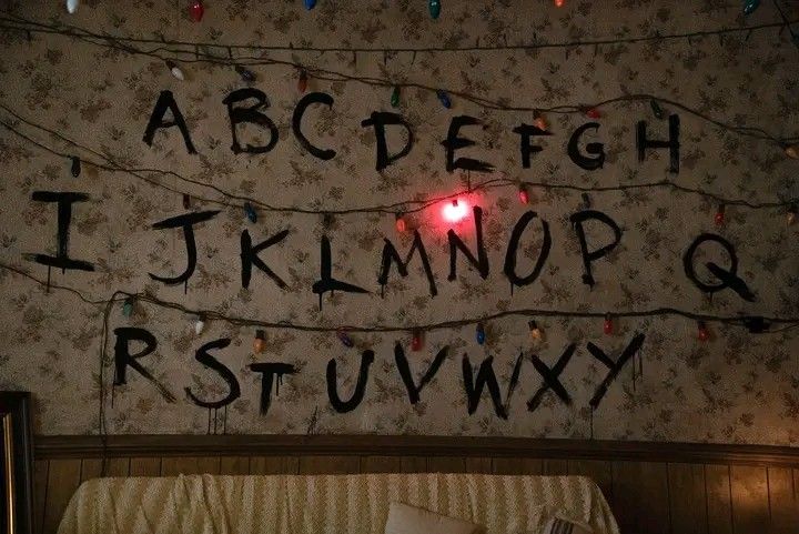 the letters are written in black ink on a wall above a bed with plaid bedspread