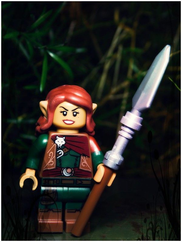 a lego figure holding a knife in front of some plants