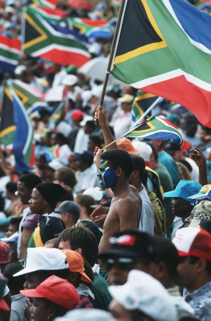 a crowd of people holding flags and wearing hats