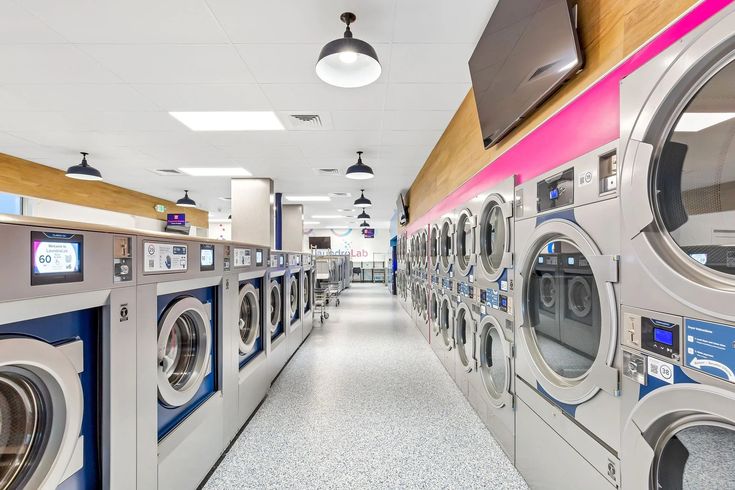 a long row of washers and dryers in a laundry room