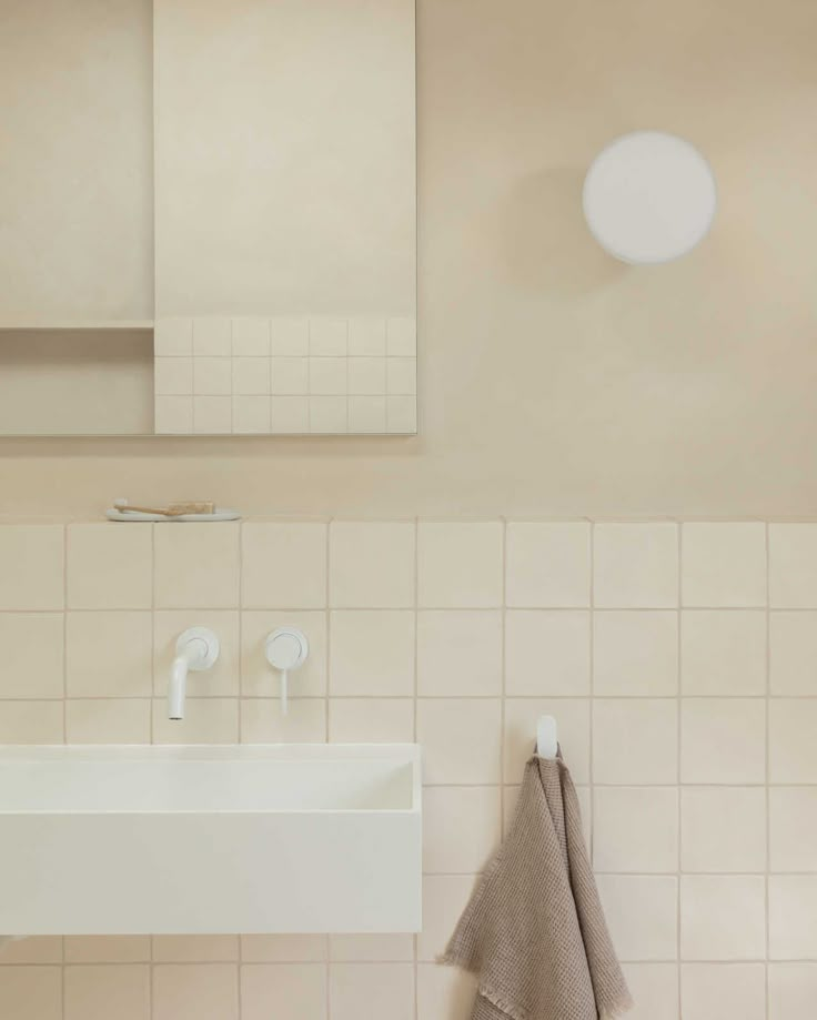 a white sink sitting next to a mirror on top of a tiled wall in a bathroom