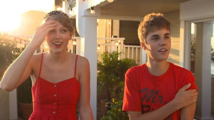 two young people standing in front of a house with their hands on their foreheads