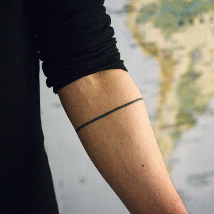 a person with a tattoo on their arm holding a cell phone in front of a map