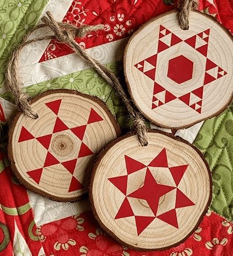 three red and white wooden ornaments on a quilt