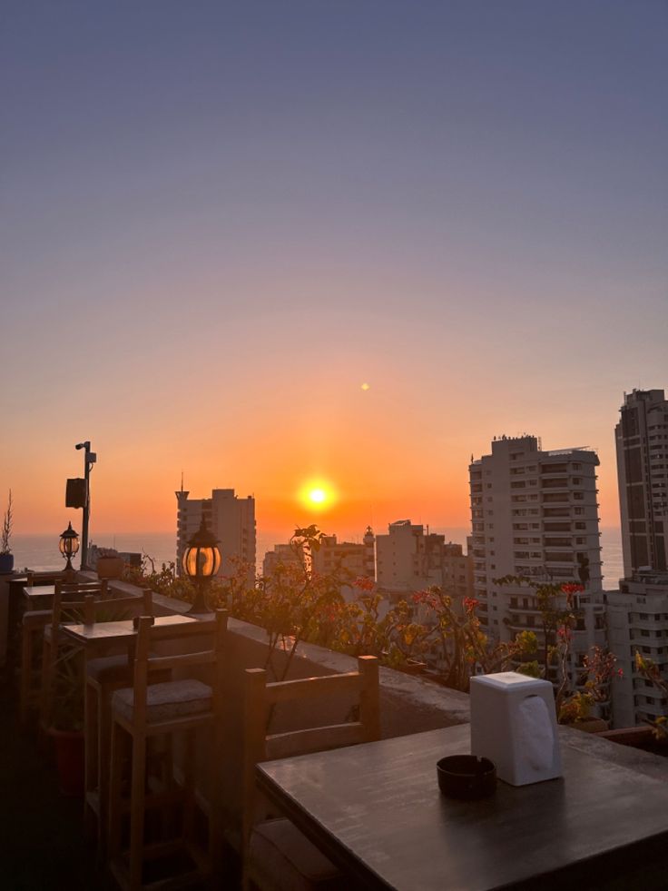 the sun is setting over some buildings and tables