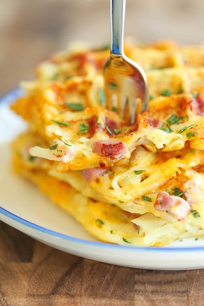 a fork sticking out of some food on a plate with cheese and bacon waffles