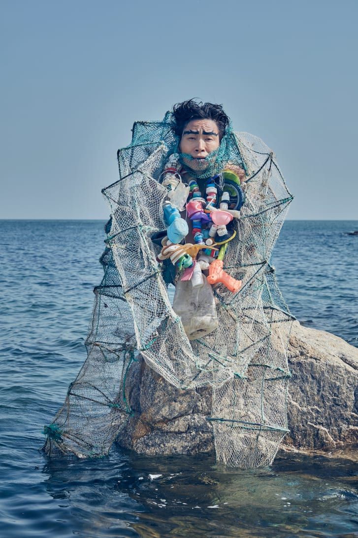 a man standing on top of a rock in the middle of the ocean with fishing nets