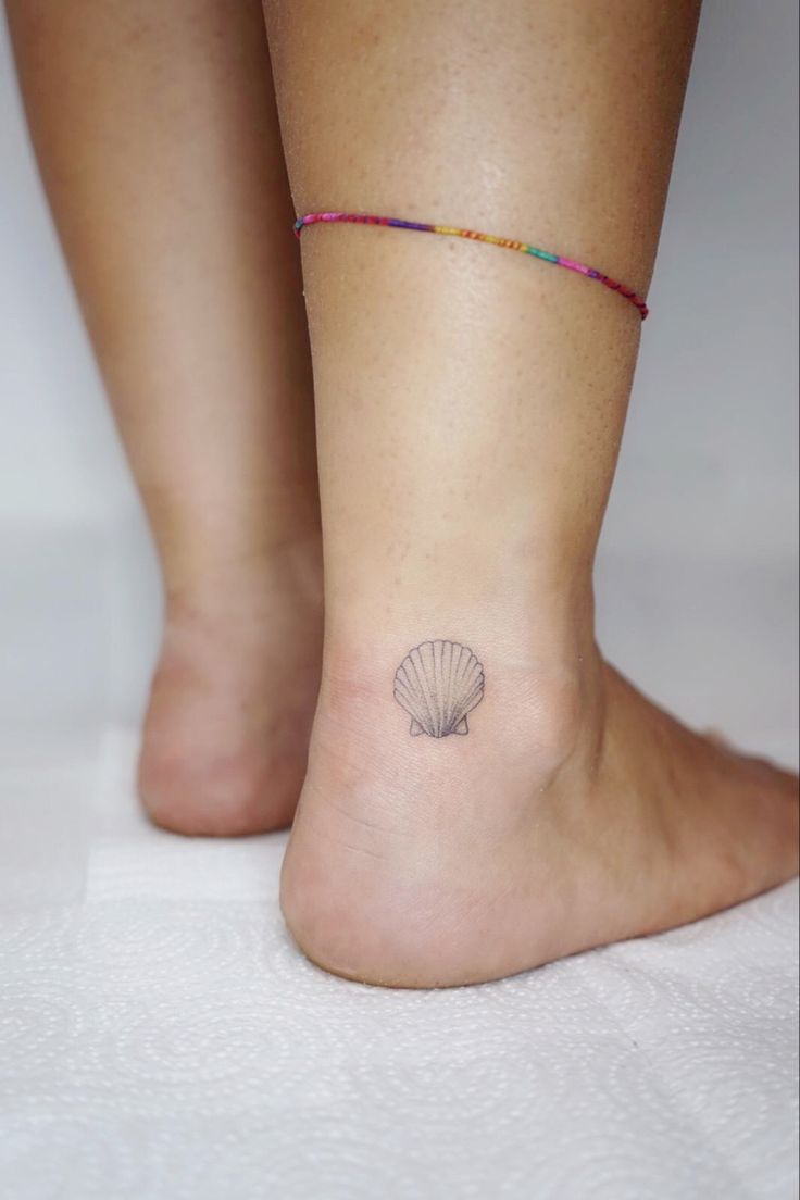 a woman's foot with a small shell tattoo on her left side calfocks