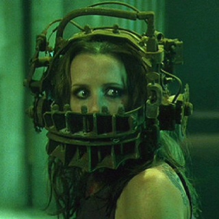 a woman wearing a mask with metal parts on her face and hair in the background