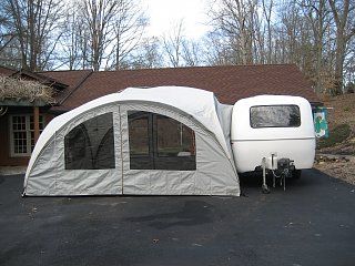 an rv parked in front of a house with a tent attached to the side of it